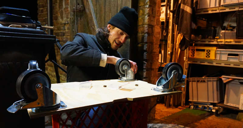 Foto von einer Person, die Rollen an ein Holzbrett schraubt