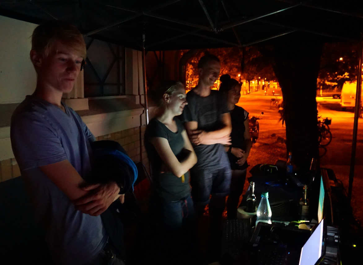 Teamfoto im Dunkeln hinter der Technik