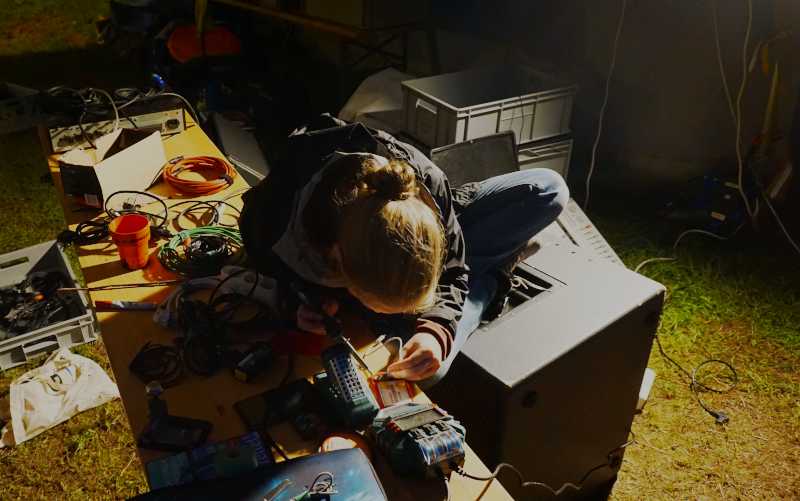 Person lötet und sitzt dabei auf einem Subwoofer